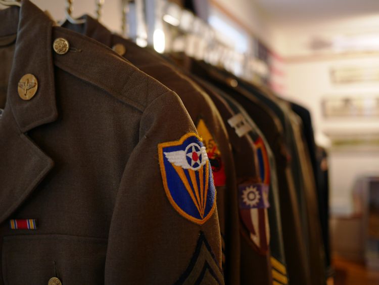 Military uniforms with patches, hung up on hangers